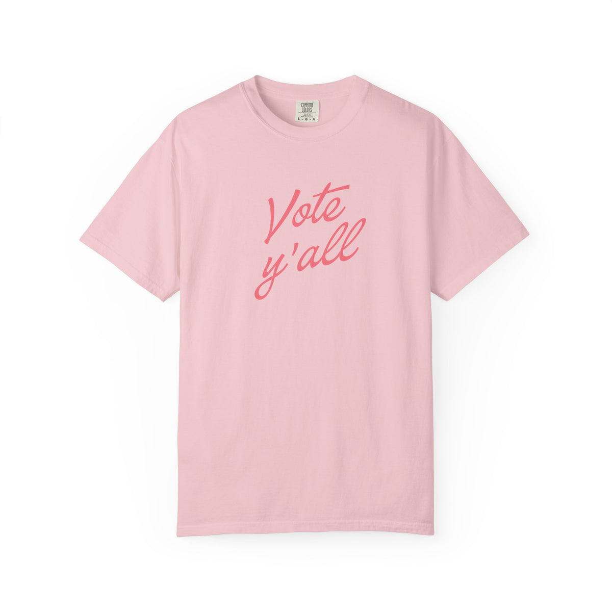 A light pink short-sleeve crewneck t-shirt with the phrase 'Vote y'all' printed in a coral-pink cursive font across the chest, displayed on a clean white background.