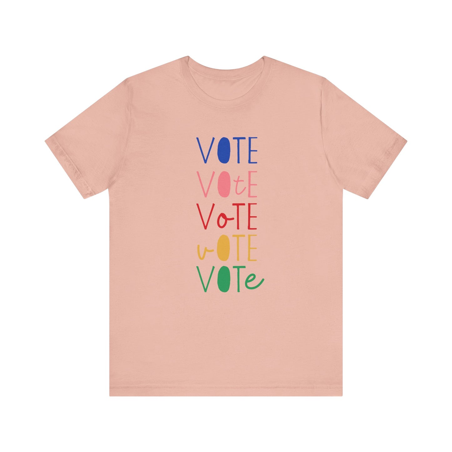 A peach short-sleeve t-shirt with a vertical graphic on the chest spelling 'VOTE' in alternating bright colors (blue, pink, red, yellow, green) with oval letterforms, shown on a plain white background.