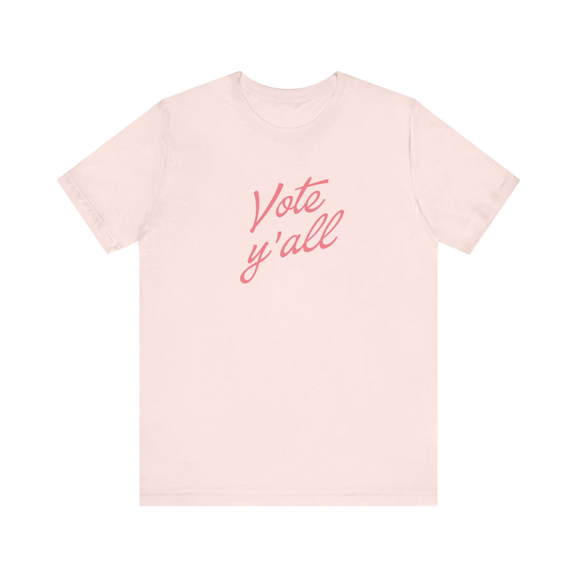 A light pink short-sleeve crewneck t-shirt featuring the phrase 'Vote y'all' printed in a pink cursive font across the chest, displayed on a clean white background.