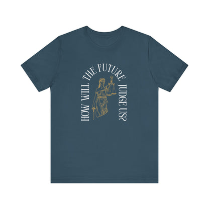 Blue t-shirt with sketch of lady justice and words in white arched around it "how will the future judge us?" 