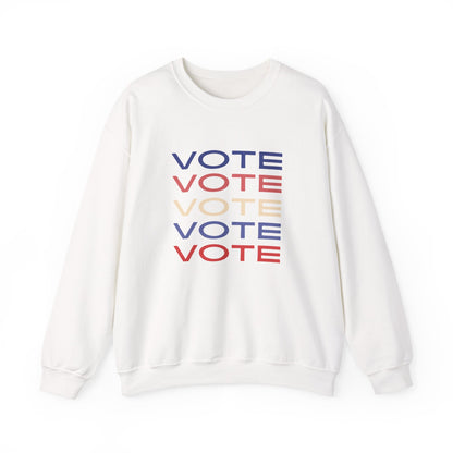 A white crewneck sweatshirt featuring a stacked graphic print of the word 'VOTE' in blue, red, and beige, displayed on a clean white background.