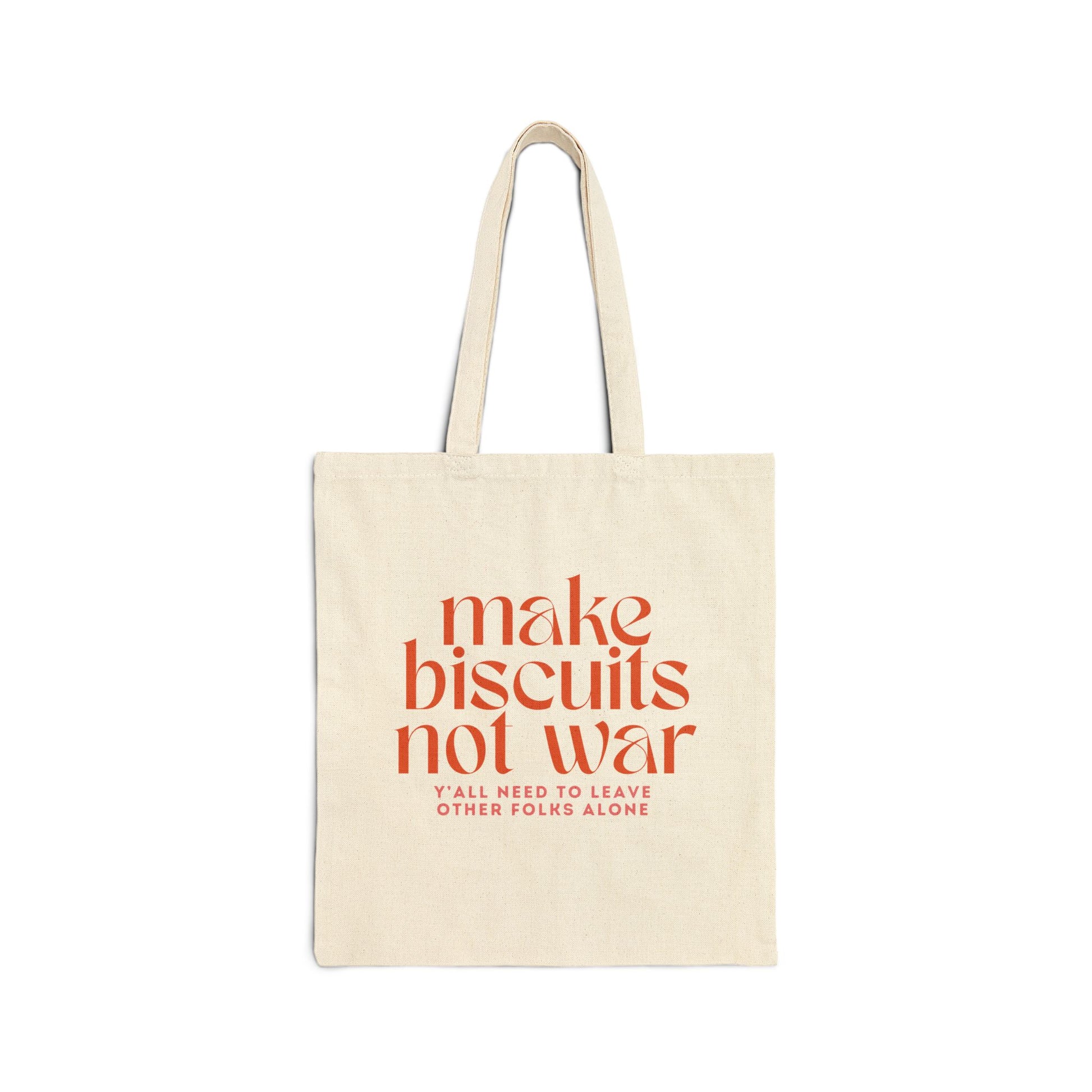 Beige canvas tote bag with orange text 'make biscuits not war' and smaller pink text 'y'all need to leave other folks alone' 