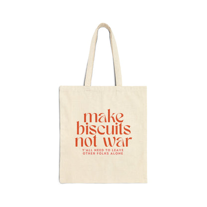 Beige canvas tote bag with orange text 'make biscuits not war' and smaller pink text 'y'all need to leave other folks alone' 
