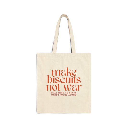 Beige canvas tote bag with orange text 'make biscuits not war' and smaller pink text 'y'all need to leave other folks alone' 