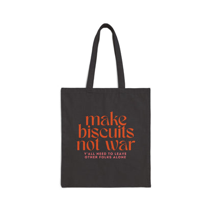 Black canvas tote bag with orange text 'make biscuits not war' and smaller pink text 'y'all need to leave other folks alone' 