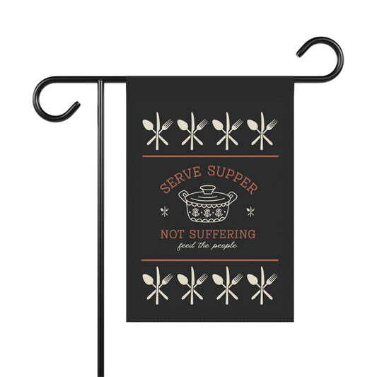 Black garden flag with white utensils graphic border around a white vintage pyrex illustration and dark orange and white words "serve supper not suffering, feed the people"