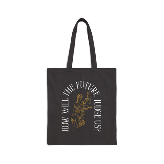 Black canvas tote bag with a design of Lady Justice and white text 'How will the future judge us?' 