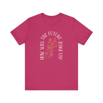 Hot pink t-shirt with sketch of lady justice and words in white arched around it "how will the future judge us?" 