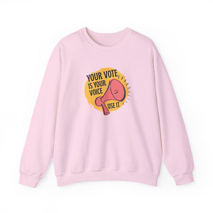 Light pink sweatshirt with a coral megaphone graphic against a bright yellow circle and black text "your vote is your voice, use it"