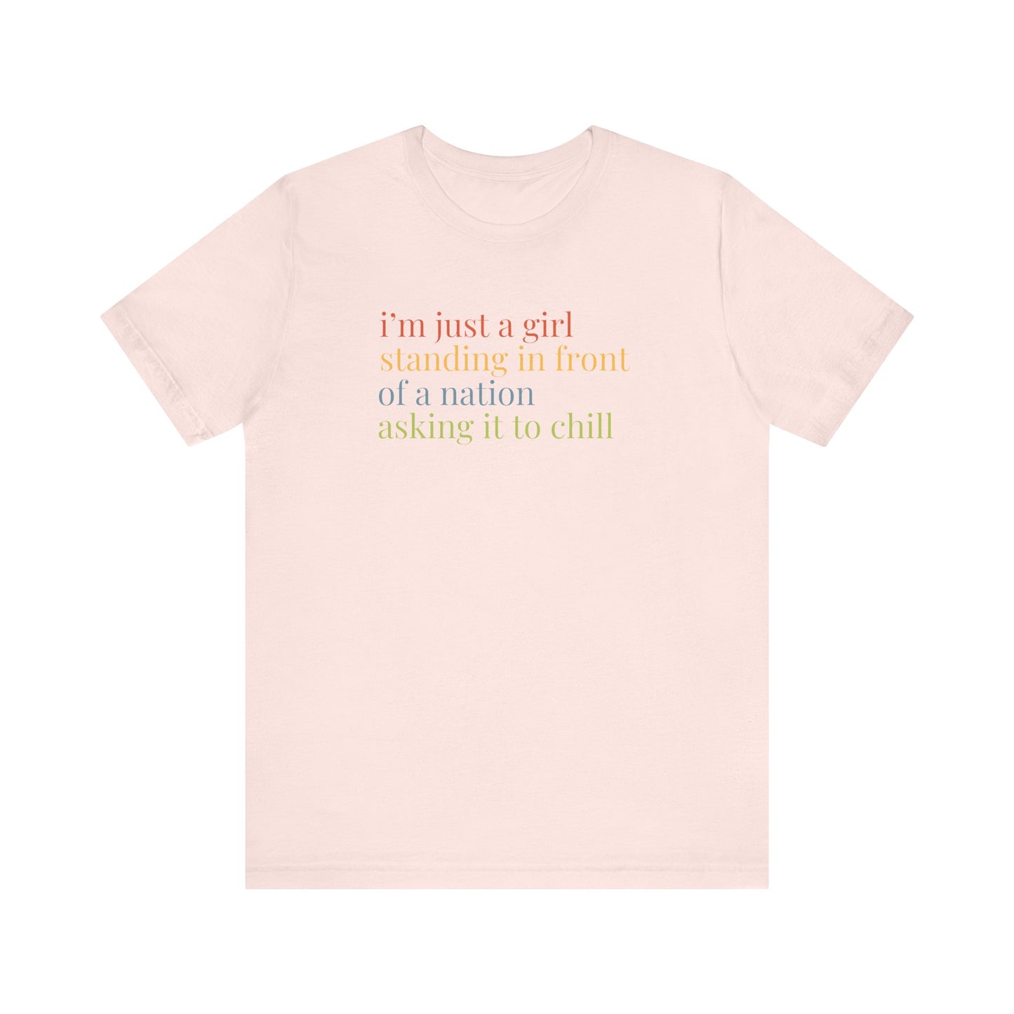 Pink t-shirt with colorful text "i'm just a girl, standing in front of a nation, asking it to chill"