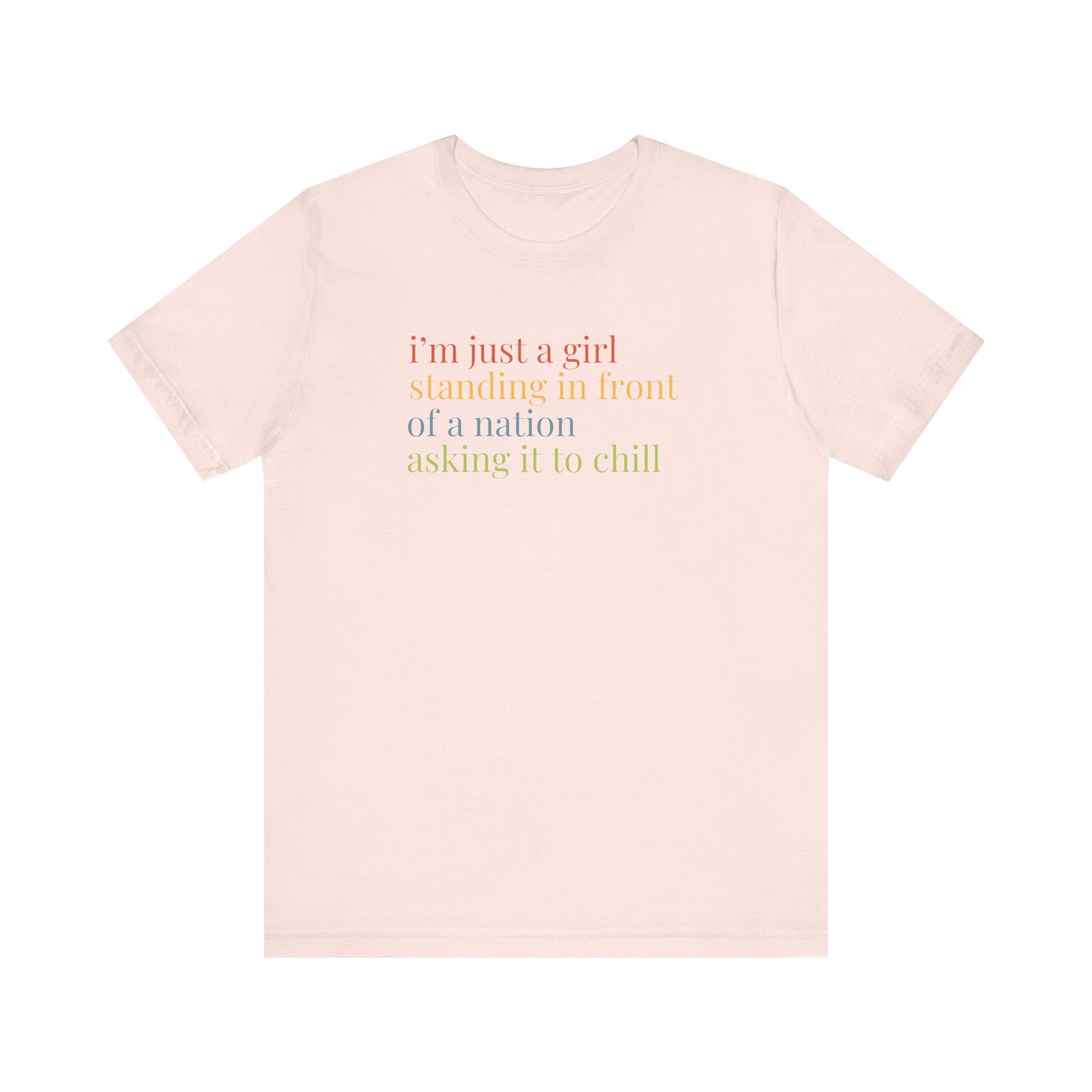 Pink t-shirt with colorful text "i'm just a girl, standing in front of a nation, asking it to chill"