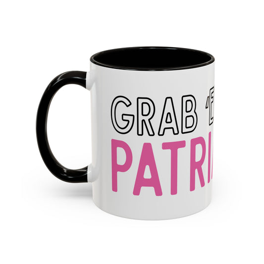 White ceramic 11 oz coffee or tea mug with black interior and handle and wraparound text 'GRAB THE PATRIOT' in black and pink