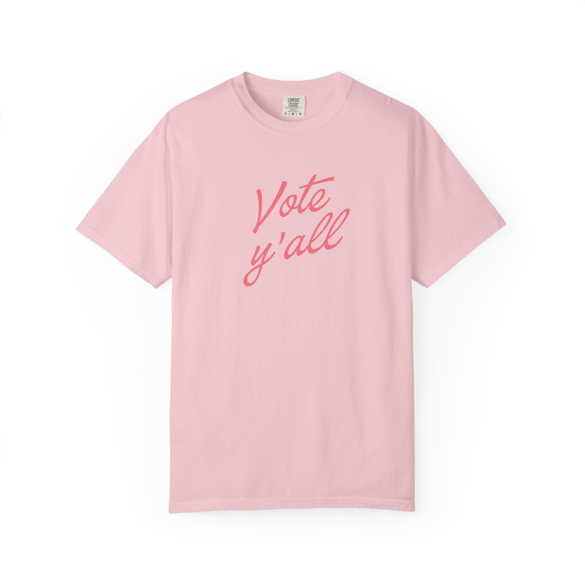 A light pink short-sleeve crewneck t-shirt with the phrase 'Vote y'all' printed in a coral-pink cursive font across the chest, displayed on a clean white background.