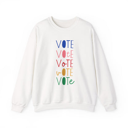 A white crewneck sweatshirt featuring a vertical graphic print of the word 'VOTE' repeated five times in alternating colors: blue, pink, red, yellow, and green.