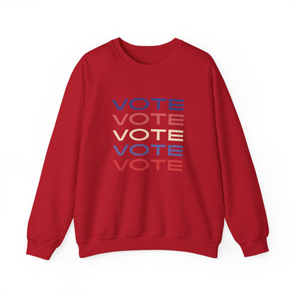 A red crewneck sweatshirt featuring a stacked graphic print of the word 'VOTE' in blue, red, and beige, displayed on a clean white background.