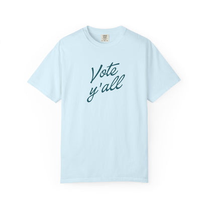 A light blue short-sleeve crewneck t-shirt with the words 'Vote y'all' printed in a dark teal cursive font across the chest, displayed on a clean white background.