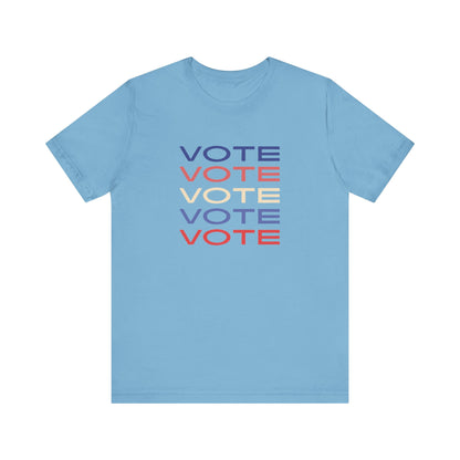 A blue short-sleeve crewneck t-shirt featuring a stacked graphic print of the word 'VOTE' in blue, red, and cream on the chest.
