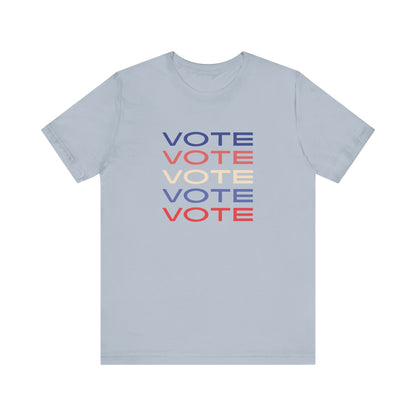 A light blue short-sleeve crewneck t-shirt featuring a stacked graphic print of the word 'VOTE' in blue, red, and cream on the chest.