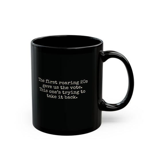 Black ceramic 11 oz coffee or tea mug with "the first roaring 20s gave us the vote. this one's trying to take it back" in cream text.