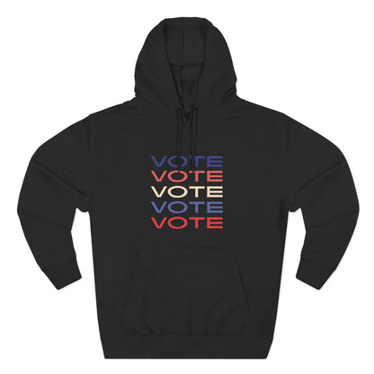 A black pullover hoodie with a front kangaroo pocket and drawstring hood, featuring a stacked 'VOTE' graphic in blue, red, and cream on the chest, displayed on a clean white background.