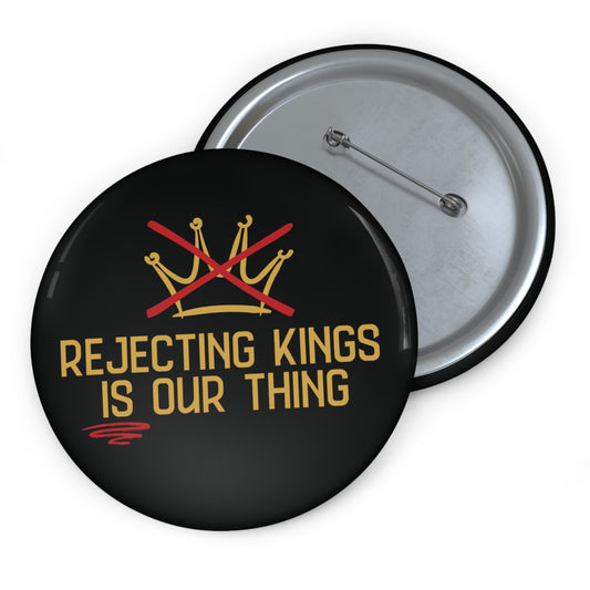 Button with 'Rejecting Kings is Our Thing' text and crossed crowns design on a black background.