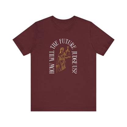 Maroon t-shirt with sketch of lady justice and words in white arched around it "how will the future judge us?" 