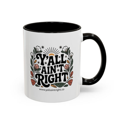 White ceramic coffee or tea mug with black interior and handle, featuring "Y'all Ain't Right" decorative text and floral elements