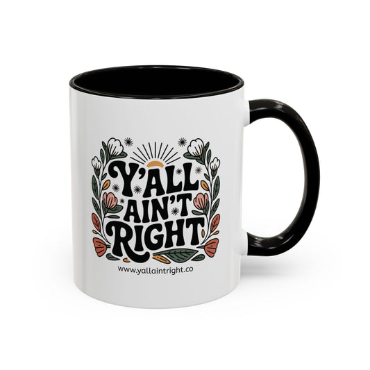 White ceramic coffee or tea mug with black interior and handle, featuring "Y'all Ain't Right" decorative text and floral elements