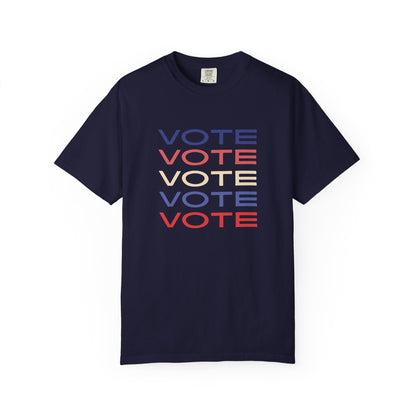 A navy blue short-sleeve crewneck t-shirt featuring a stacked graphic print of the word 'VOTE' in blue, red, and beige, displayed on a clean white background.
