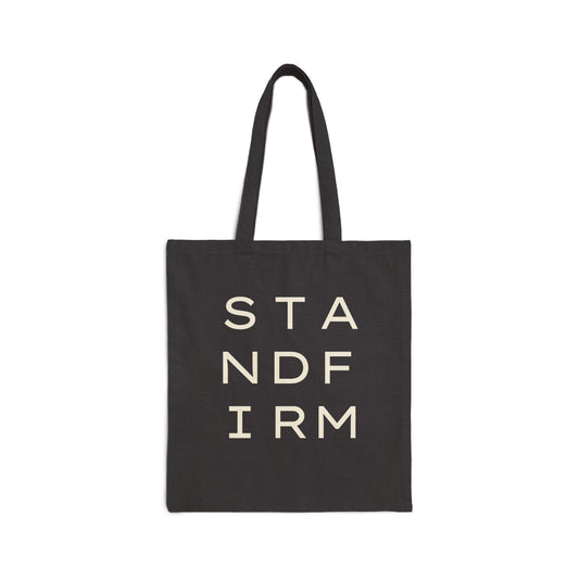Black canvas tote bag with 'STAND FIRM' cream text