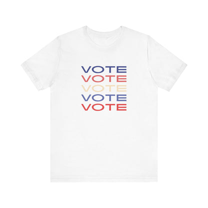 A white short-sleeve crewneck t-shirt featuring a stacked graphic print of the word 'VOTE' in blue, red, and cream on the chest.