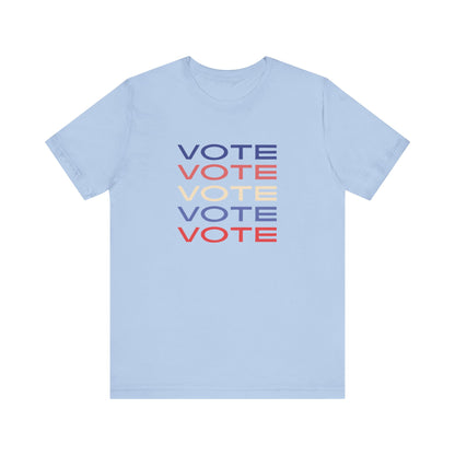 A light blue short-sleeve crewneck t-shirt featuring a stacked graphic print of the word 'VOTE' in blue, red, and cream on the chest.