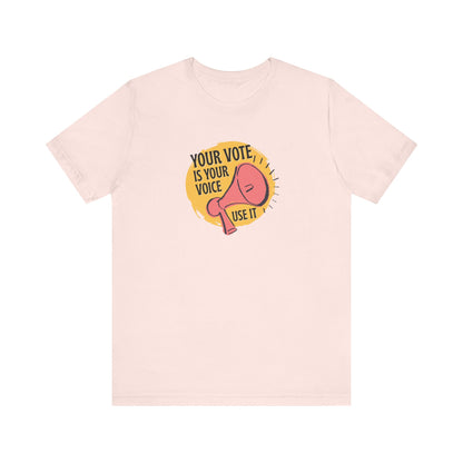 Light pink t-shirt with a coral megaphone graphic over bright yellow circle and black text "your vote is your voice, use it" 