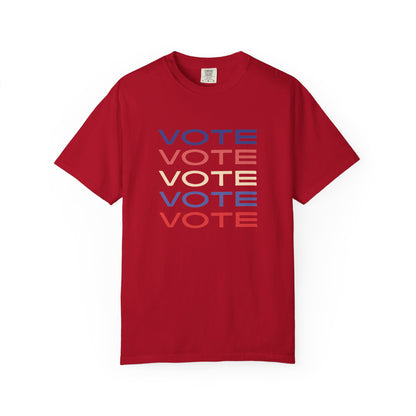 A red short-sleeve crewneck t-shirt featuring a stacked graphic print of the word 'VOTE' in blue, red, and beige, displayed on a clean white background.