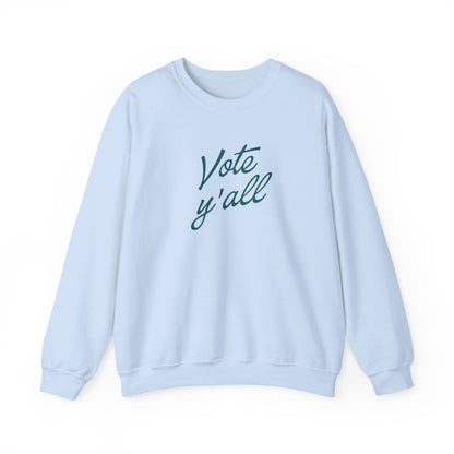 A light blue crewneck sweatshirt with the words 'Vote y'all' printed in a dark blue cursive font on the chest