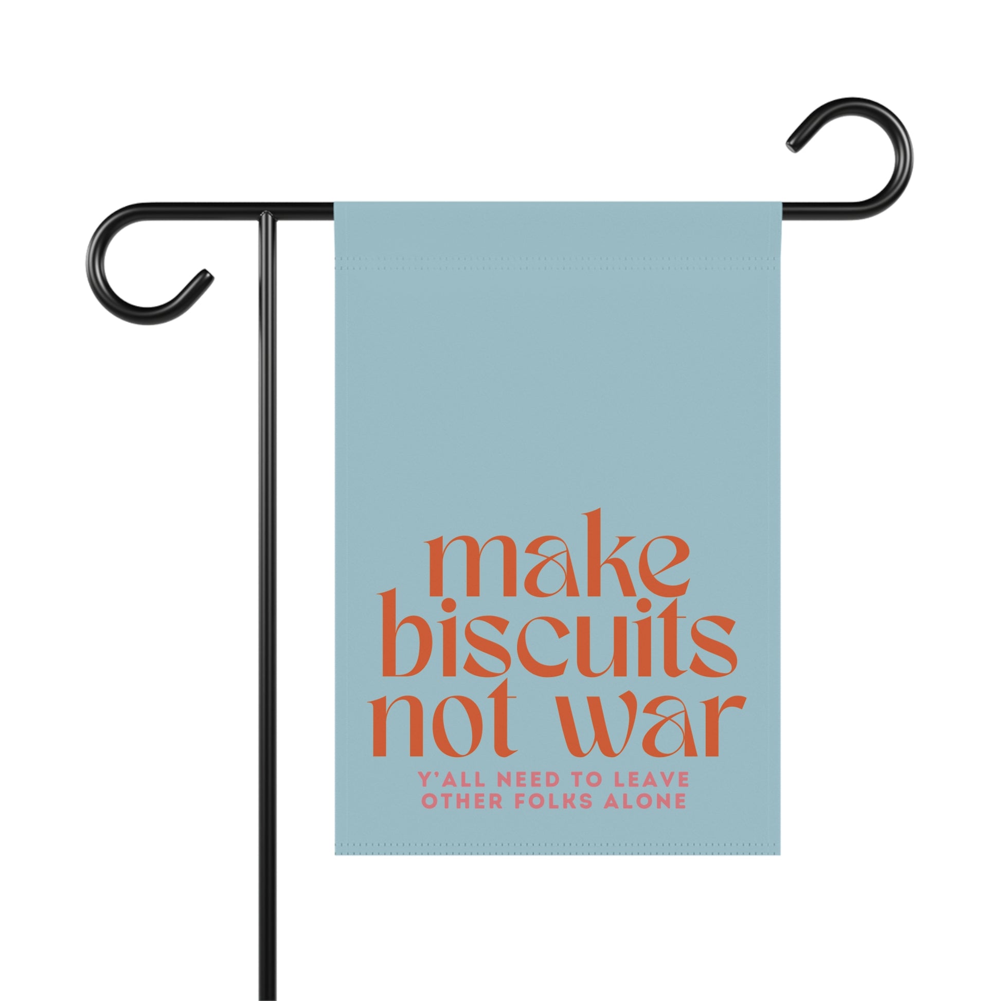 Light blue garden flag with orange 'make biscuits not war' text and dark pink smaller text "y'all need to leave other folks alone"