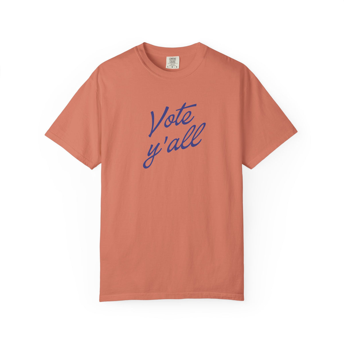 A short-sleeve crewneck t-shirt in a muted terracotta color, featuring the phrase 'Vote y'all' printed in blue cursive script across the chest, displayed on a clean white background.