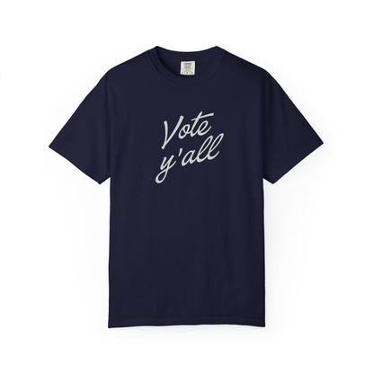 A short-sleeve crewneck t-shirt in a navy blue color, featuring the phrase 'Vote y'all' printed in gray cursive script across the chest, displayed on a clean white background.