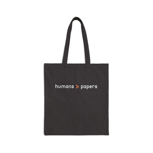 Black canvas tote bag with 'humans > papers' white text