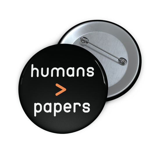 Black pin button with 'humans > papers' white text