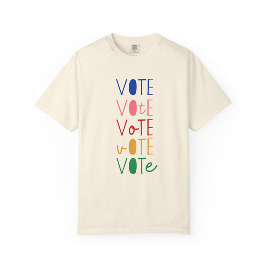 An off-white short-sleeve t-shirt with a vertical graphic spelling 'VOTE' in alternating blue, pink, red, yellow, and green colors, displayed on a clean white background.