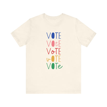 A cream short-sleeve t-shirt with a vertical graphic on the chest spelling 'VOTE' in alternating bright colors (blue, pink, red, yellow, green) with oval letterforms, shown on a plain white background.