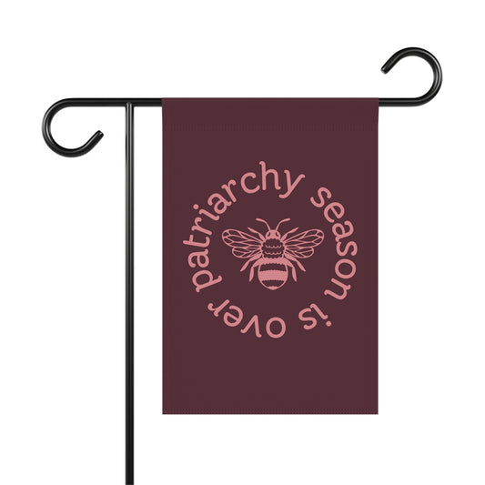 Maroon garden flag with pink "patriarchy season is over" text circling around a queen bee graphic background