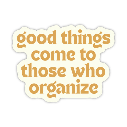 A die-cut sticker with a wavy scalloped border, featuring the phrase 'good things come to those who organize' in a warm mustard-gold serif font on an off-white background.