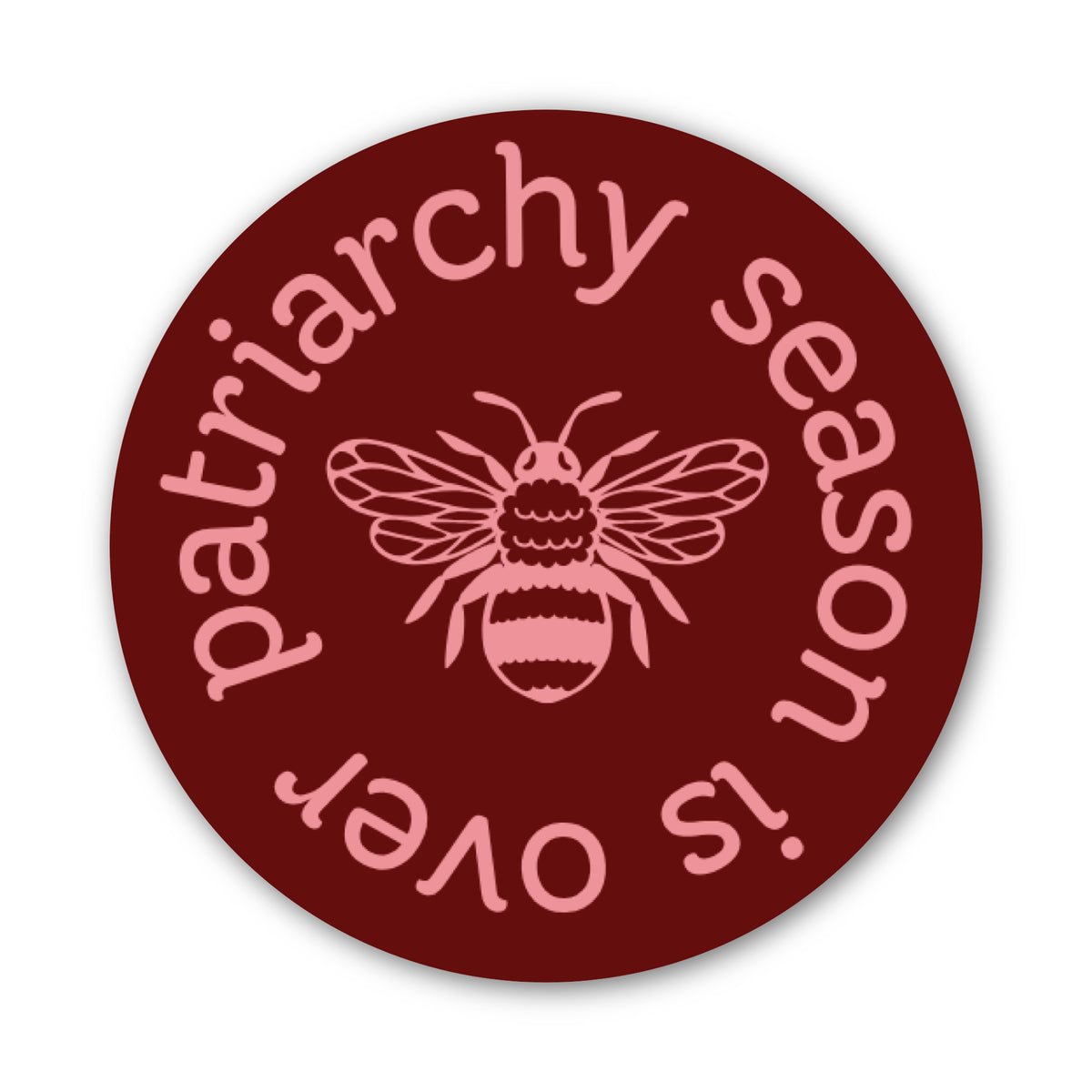 A round sticker or decal with a dark red background, featuring a pink bee in the center and the text 'patriarchy season is over' in pink around the edge.