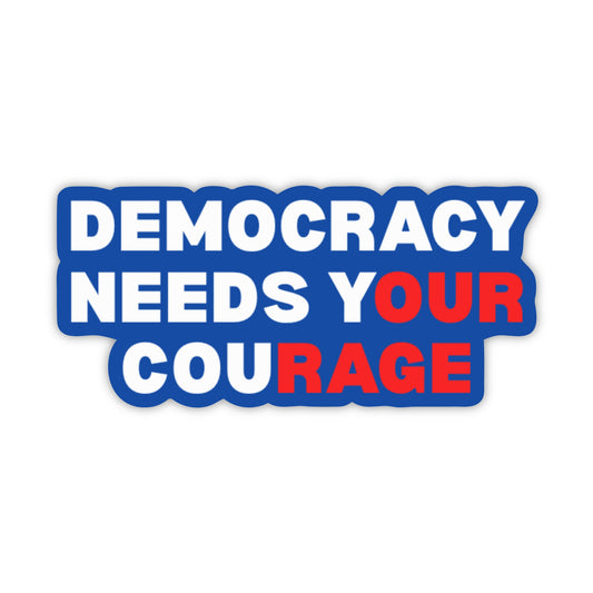 A die-cut sticker with the text 'DEMOCRACY NEEDS YOUR COURAGE' in bold white and red lettering on a blue background, shown on a plain white studio background.